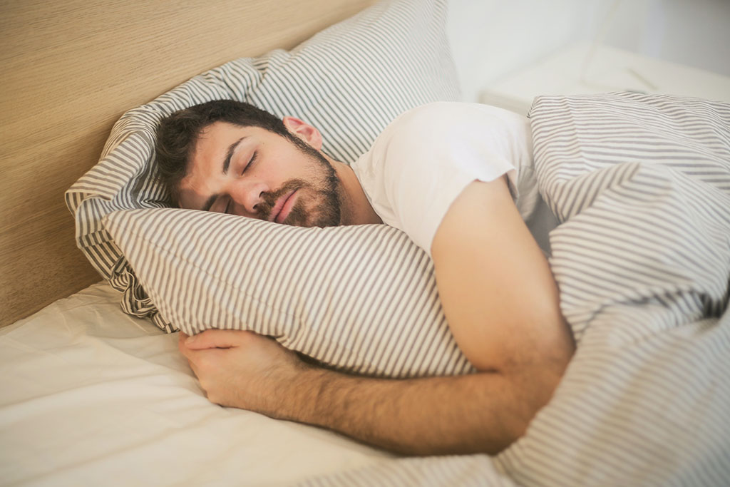 Man comfortably sleeping in bed so he can enhance his ability to speed read.