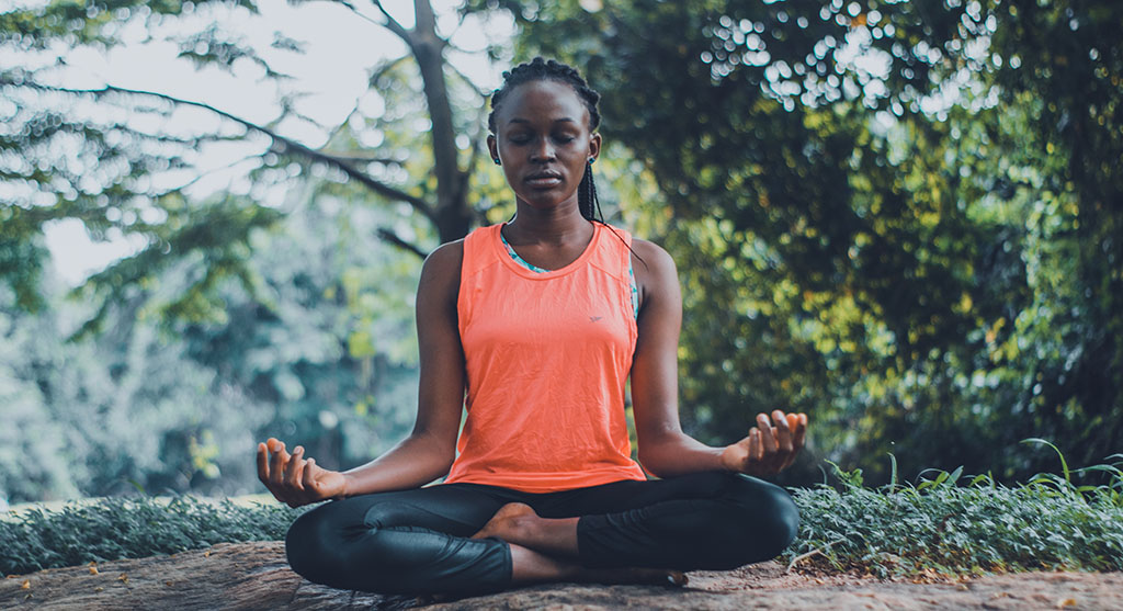 Woman meditating in nature to calm her mind and help her read faster.