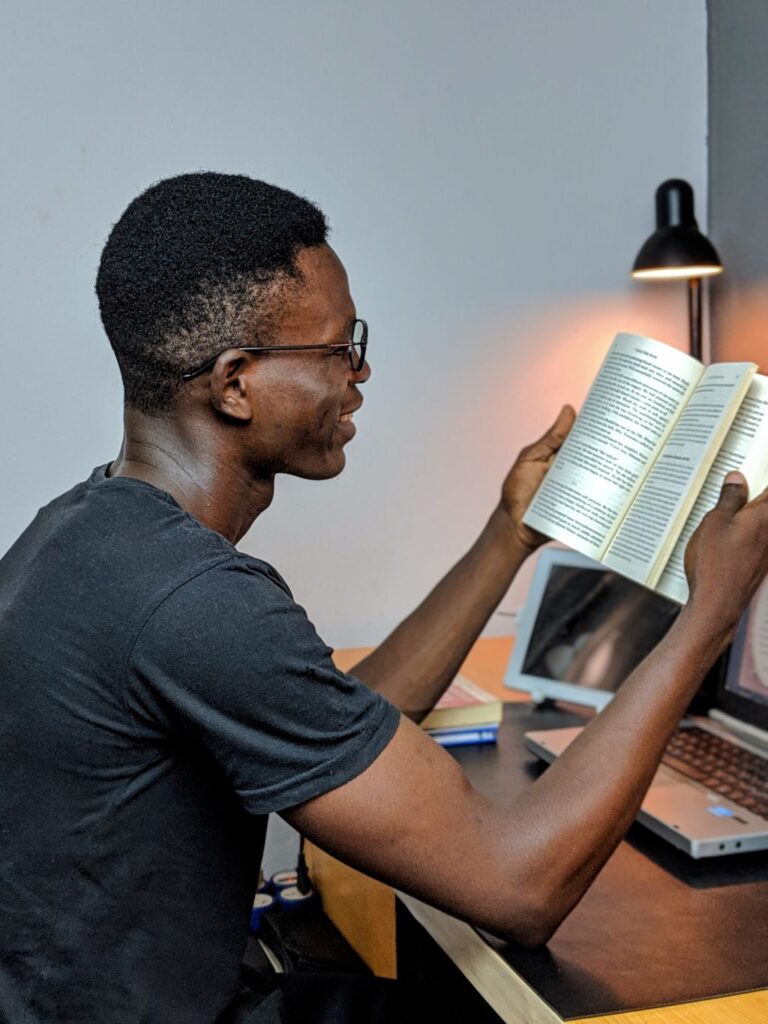 Man holding book up at an angle so he does not need to bend his neck and as a speed reading technique.