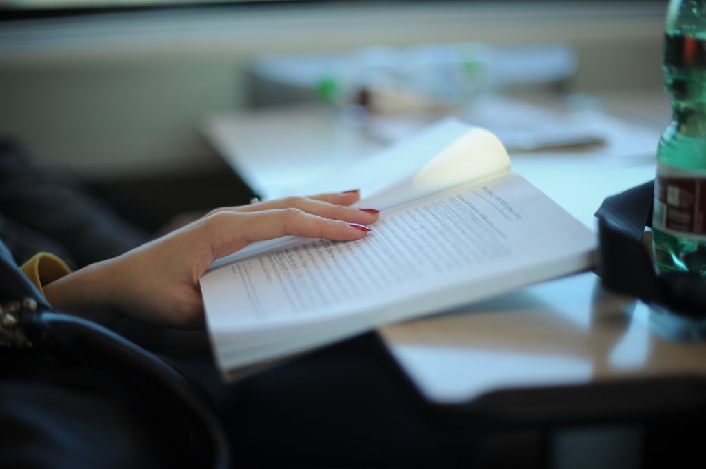 Woman using finger as a  guide to trace her words as she reads as a speed reading technique.